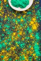 Free photo green and yellow holi powder splatter on black background