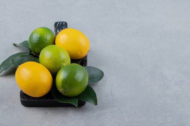 Green and yellow lemons on black cutting board