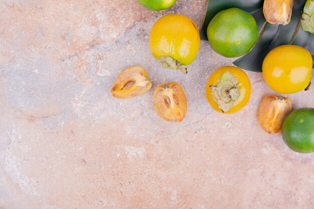 Green and yellow mandarins on pink table.