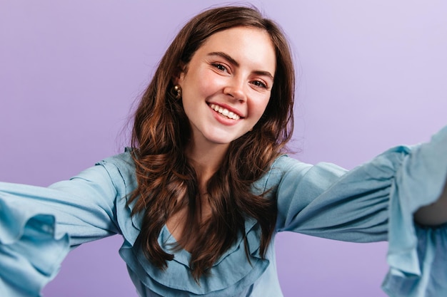 Free photo greeneyed girl in high spirits looks into camera selfie of young brunette with snowwhite smile and nude makeup