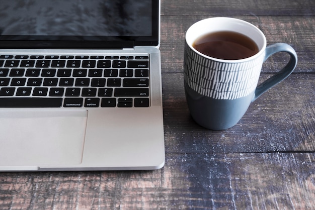 Grey laptop with coffee on wooden table