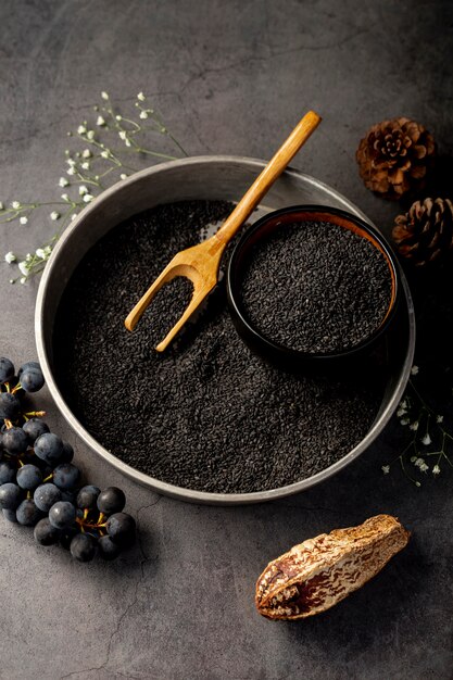 Grey metallic plate filled with poppy seeds and grapes on a grey background