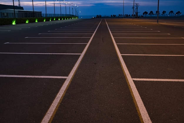 Grey road with white lines and signs against blue sky