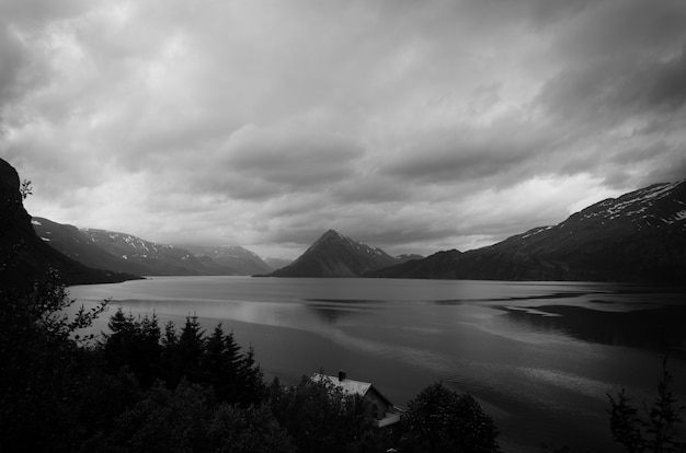 Grey-scale shot of the lake surrounded by mountains and trees