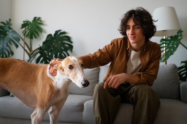 Free photo greyhound dog with male owner at home on couch