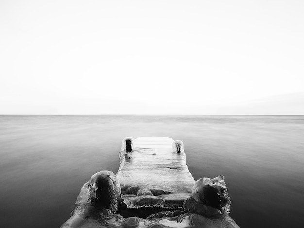 Free photo greyscale of a bridge covered in the ice on the sea under the sunlight