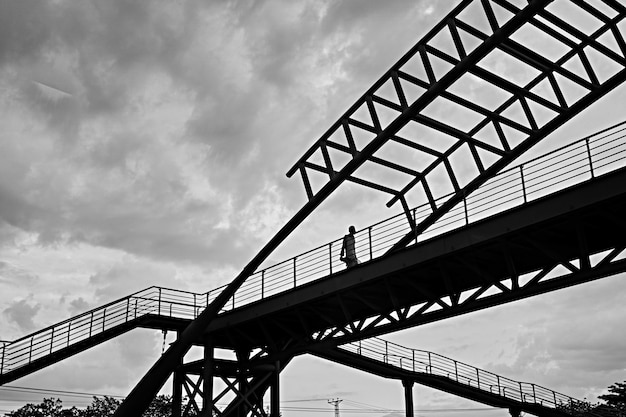 Free Photo greyscale low angle shot of a male walking through a bridge