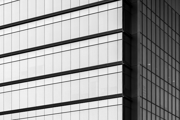 Greyscale of a modern building with glass windows under sunlight