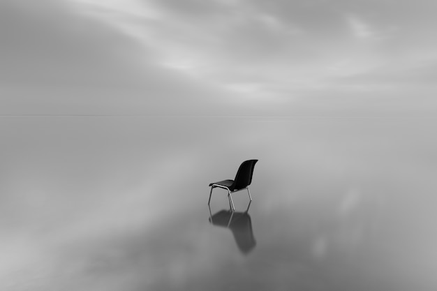 Free photo greyscale shot of a chair on a water surface with a reflection on a rainy day