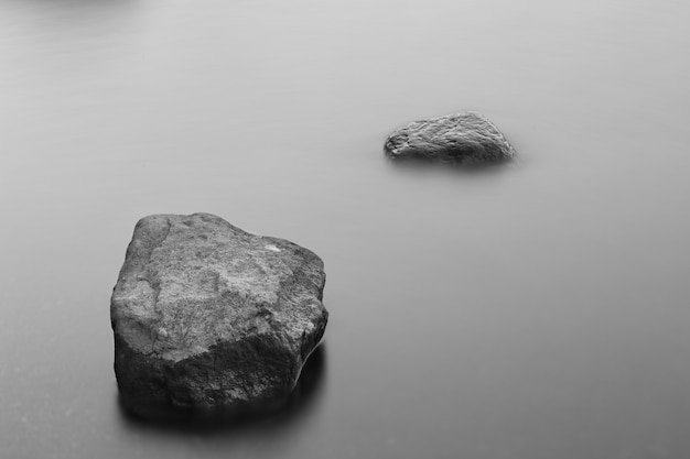 Free photo greyscale shot of rock formations in the frozen ocean covered in fog