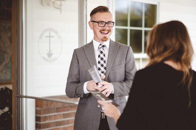 Free photo greyscale shot of a suited man greeting and welcoming a female wearing a black shirt