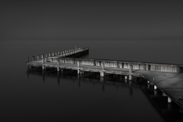 Free Photo greyscale shot of a wooden pier near the sea during daytime