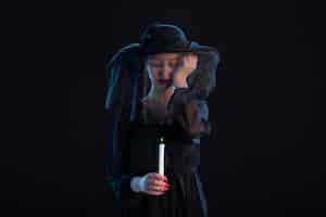 Free photo grieving female dressed in black with burning candle on black surface sadness funeral death