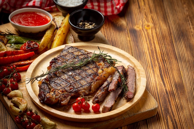 Free photo grilled beef steak on the dark wooden surface.