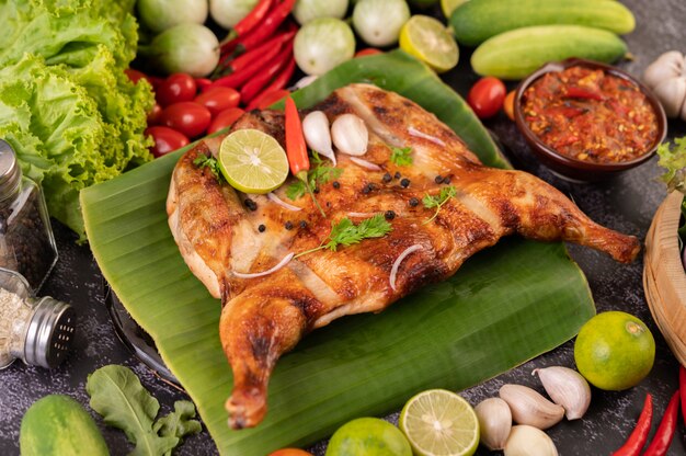 Grilled chicken on a plate with chili peppers, garlic sauce and sprinkled with pepper seeds.