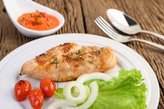 Free Photo grilled chicken on a white plate with tomatoes, salad, onion and chili sauce.