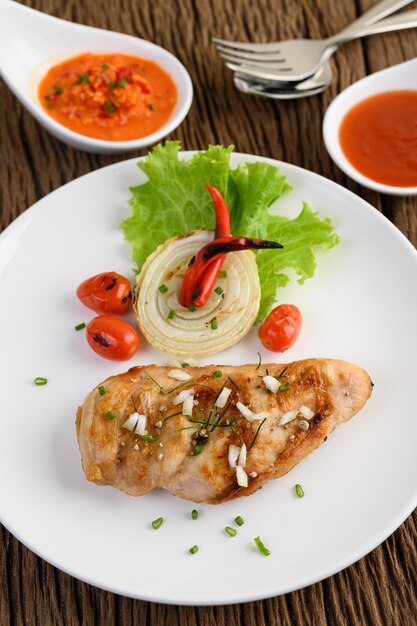 Free Photo grilled chicken on a white plate with tomatoes, salad, onion, chili and sauce.