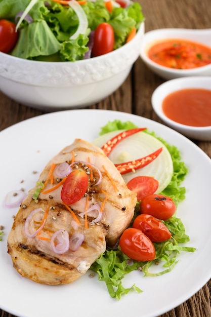 Free Photo grilled chicken on a white plate with tomatoes, salad, onion, chili and sauce.