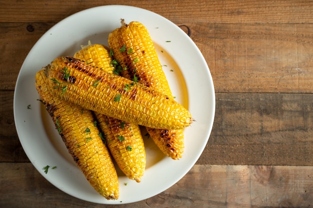 Grilled corn cobs on wood background.