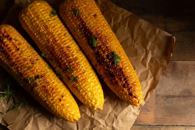 Grilled corn cobs on wood background.