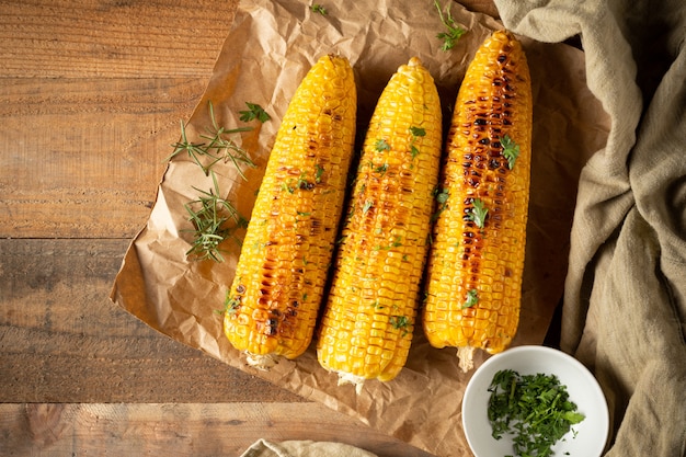 Grilled corn cobs on wood background.