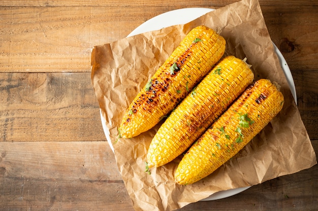 Grilled corn cobs on wood background.