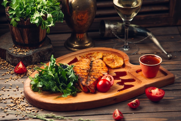 Grilled fish fillet with tomato,red sauce, herbs and a glass of white wine.