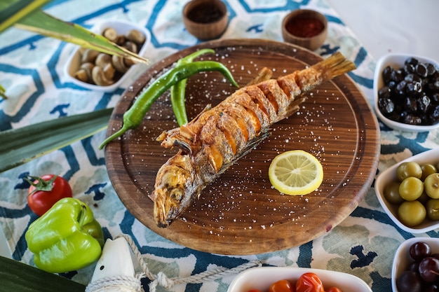 Free photo grilled fish on the wooden board salted lemon pickles