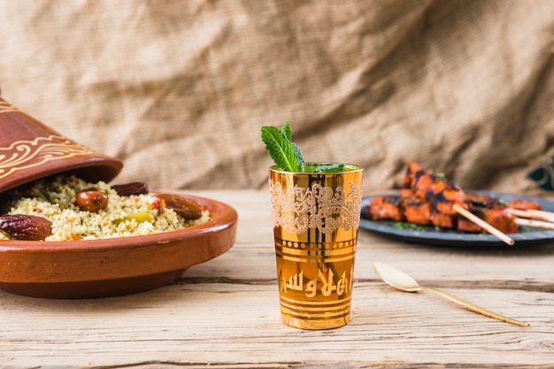 Free photo grilled meat and quinoa salad with dried plums near cup on table