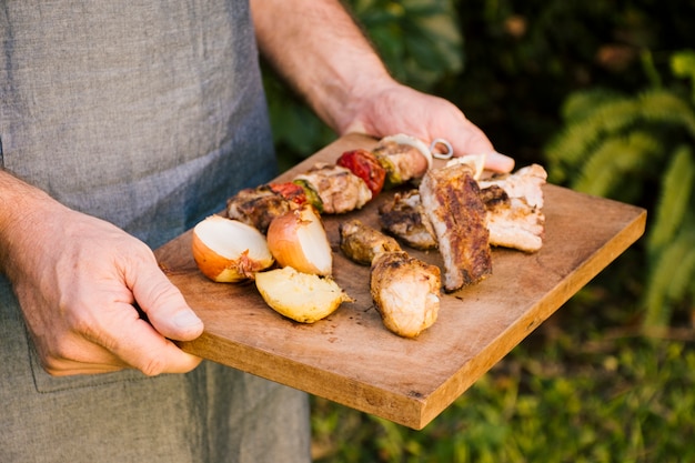 Free photo grilled meat and vegetables on wooden desk in hands