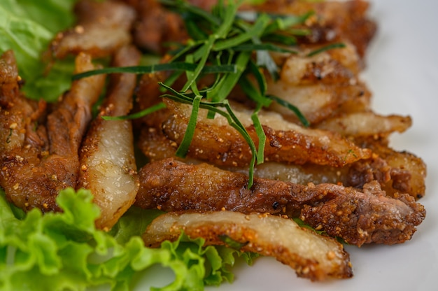 Grilled pork neck on a white plate on a wooden table