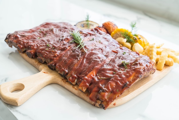 Free Photo grilled rib pork with barbecue sauce and vegetable and frech fries on wooden cutting board