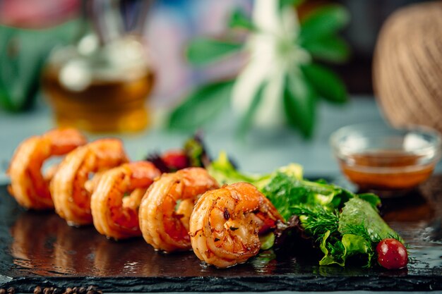 grilled shrimp with fresh herbs salad on black stone board