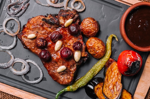 Grilled steak in cherry sauce with onion pepper potato eggplant top view