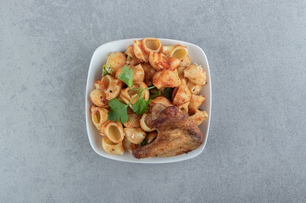 Free photo grilled wing and seashell pasta in white bowl.