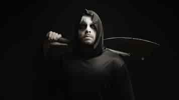 Free photo grim reaper over black background with axe in his hands. halloween costume.