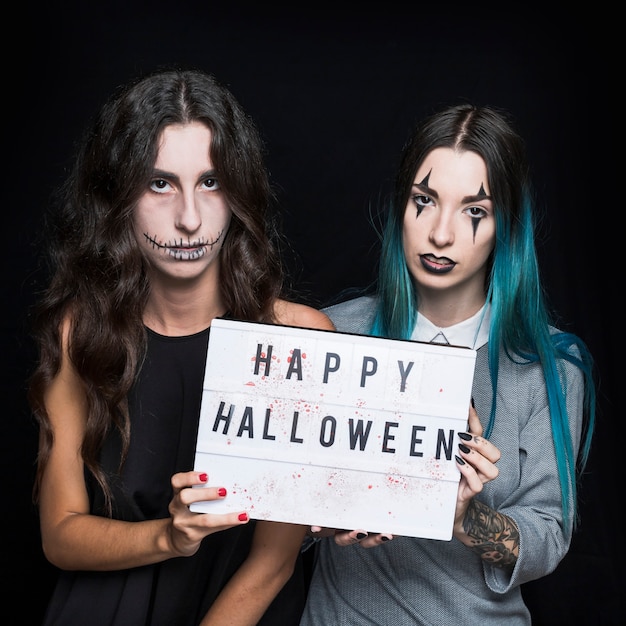 Free Photo grim young women with greeting signboard