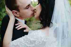 Free photo groom and bride kissing standing outside