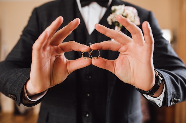 Free photo groom demonstrates two wedding rings, without face