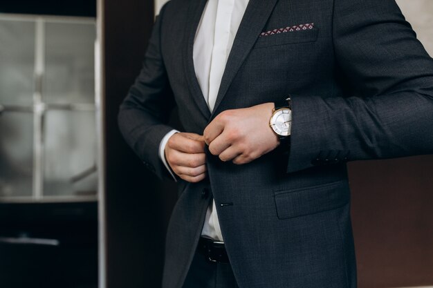 Groom fastens the buttons of his wedding suit