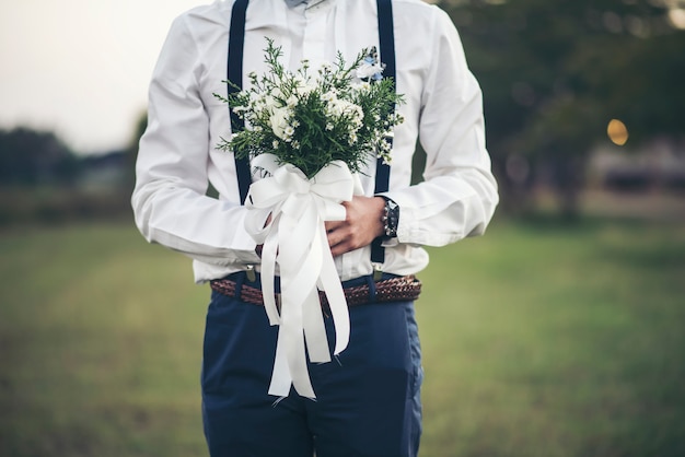 Free photo groom hand holding flower of love in wedding day