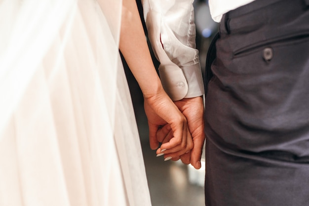 Free photo groom holds bride's fingers tender in his arm