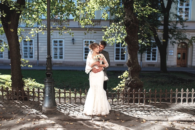 Free photo groom hugs bride against the building