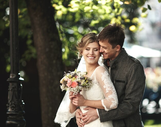 Groom hugs bride in the park