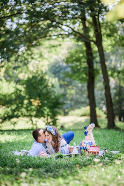 Free photo groom hugs bride tender lying with her on the blanket during picnic in a green park