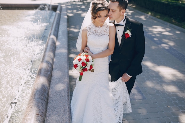 Free Photo groom kissing the bride close to the fountain