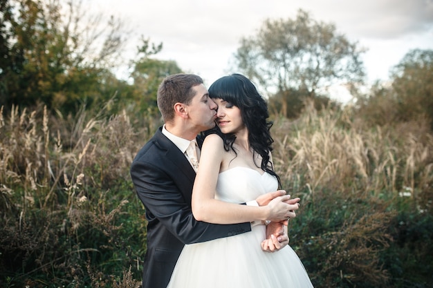 Free Photo groom kissing his wife outdoors