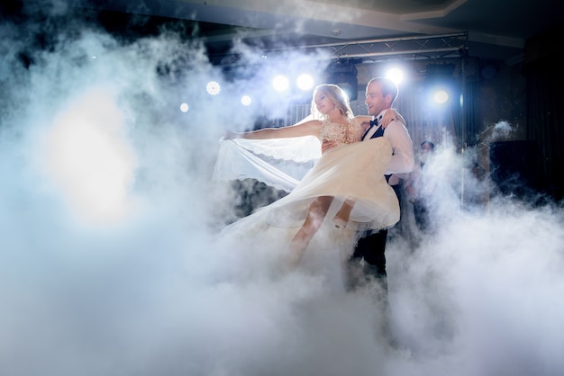 Free photo groom whirls bride in the smoke dancing for the first time