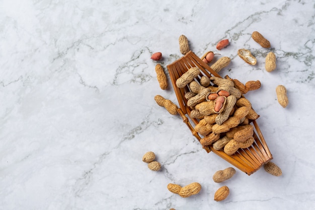 Groundnuts in wooden plate put on white marble floor