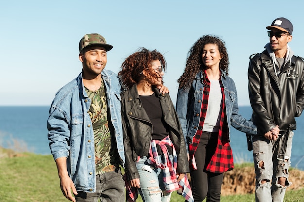 Group of african friends walking outdoors near beach.